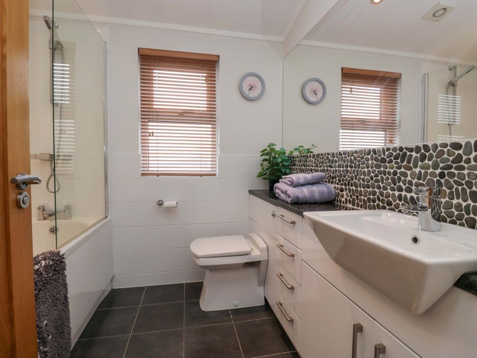 A bathroom with a sink, toilet, and bathtub at Waters Edge Lodge Windermere