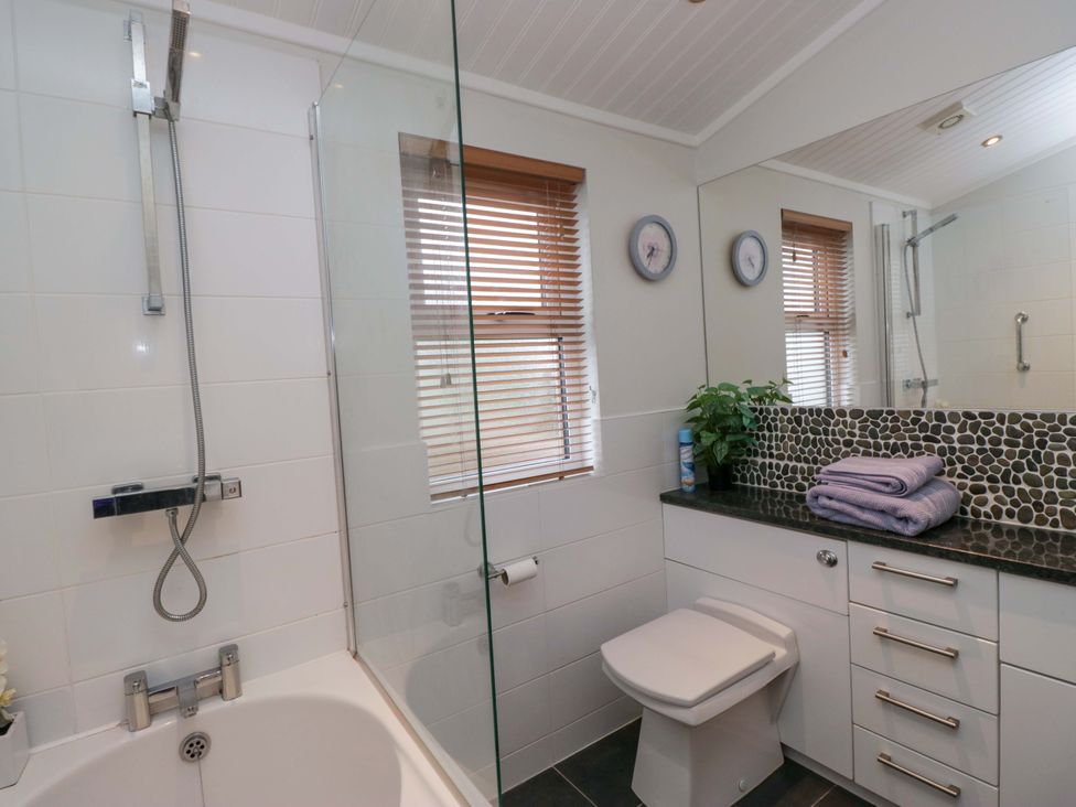 A bathroom with a bathtub, shower, and sink at Waters Edge Lodge in Windermere