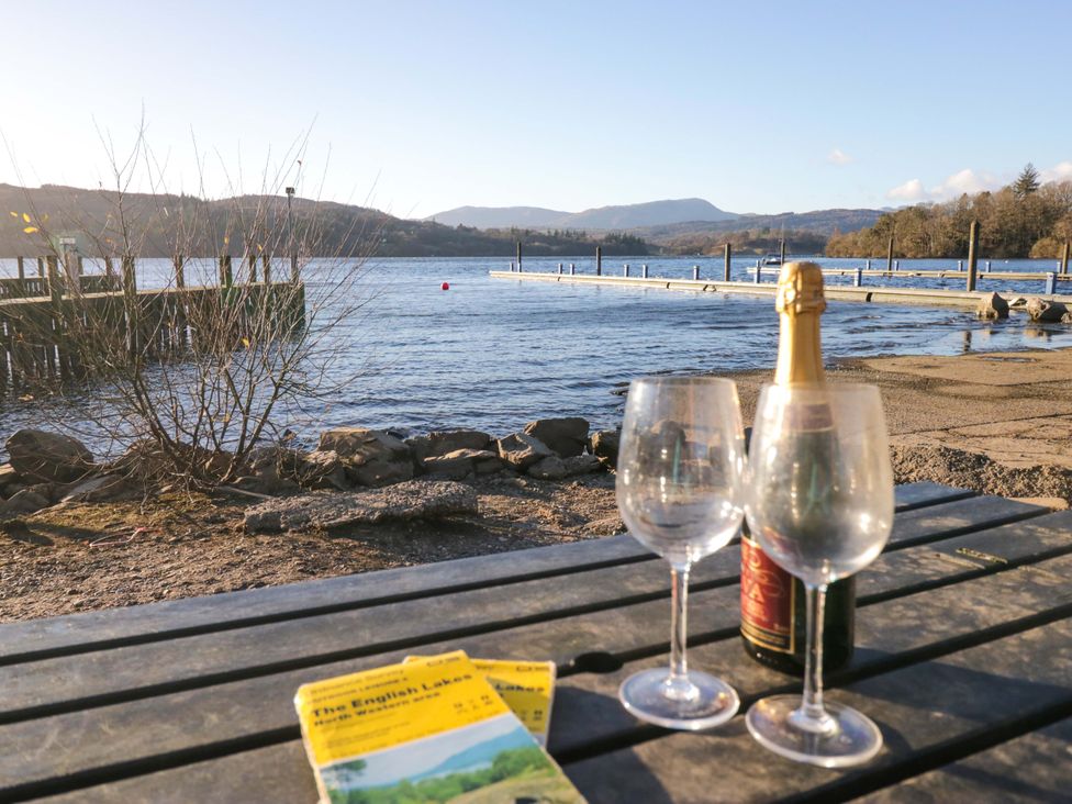 A table with drinks and a guidebook near a lake at Waters Edge Lodge in Windermere