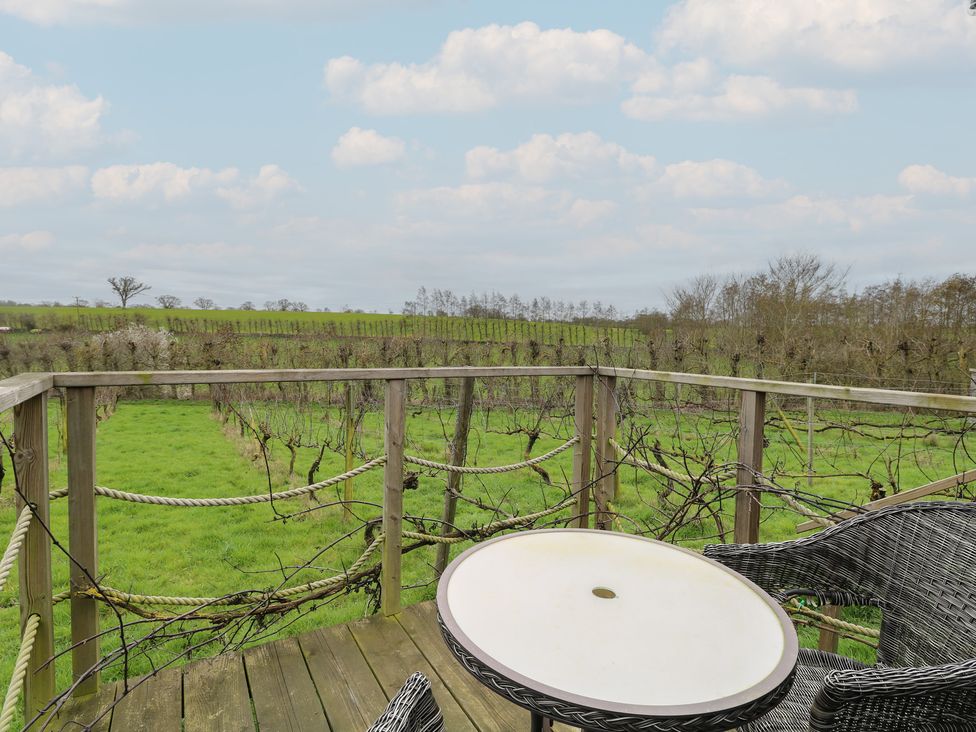 A table and chair overlooking a vineyard at Vine View near Halesworth
