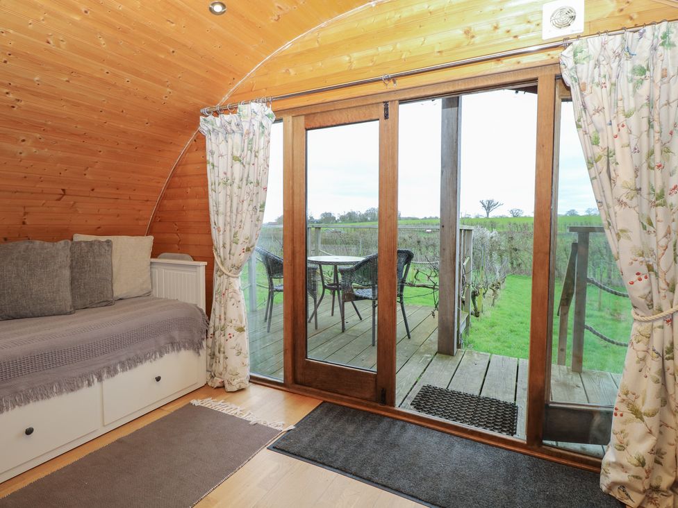 A snug with a couch and sliding door leading to a deck at Vine View near Halesworth