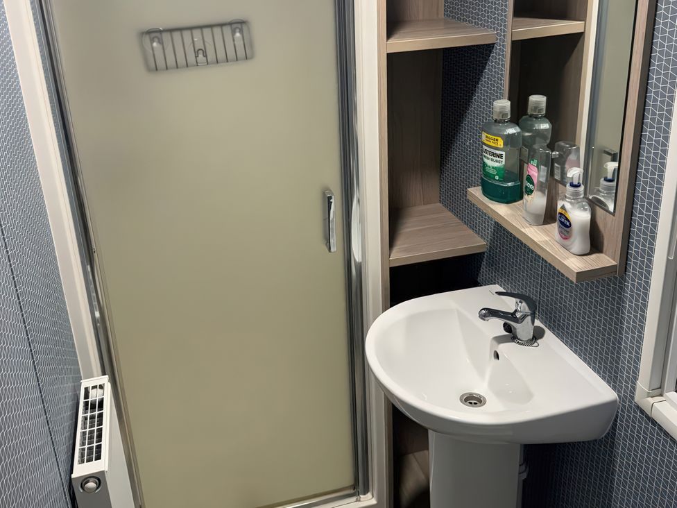 A bathroom with a shower, sink, and shelf at N5 in Ilfracombe