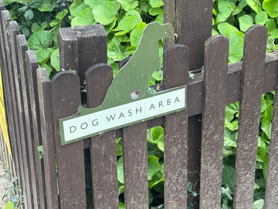 A sign indicating a dog wash area on a fence