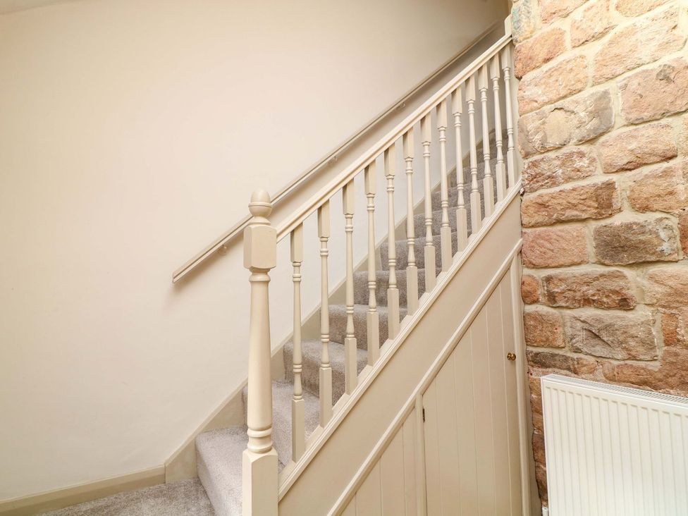 A staircase with a handrail and stone wall at The Annexe in Belper