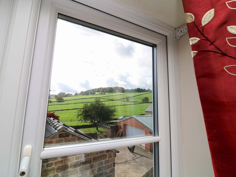 A window view of a field with trees and buildings at The Annexe in Belper