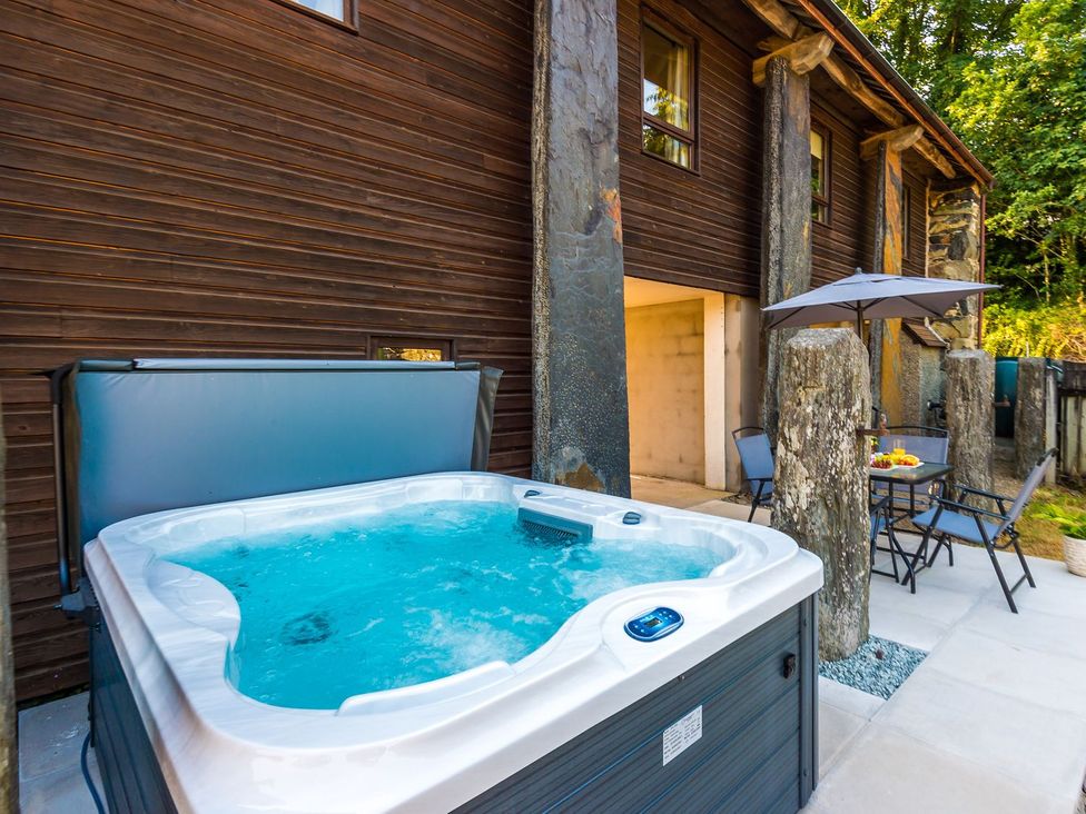 An outdoor area with a jacuzzi and a table with chairs at Idris Barn