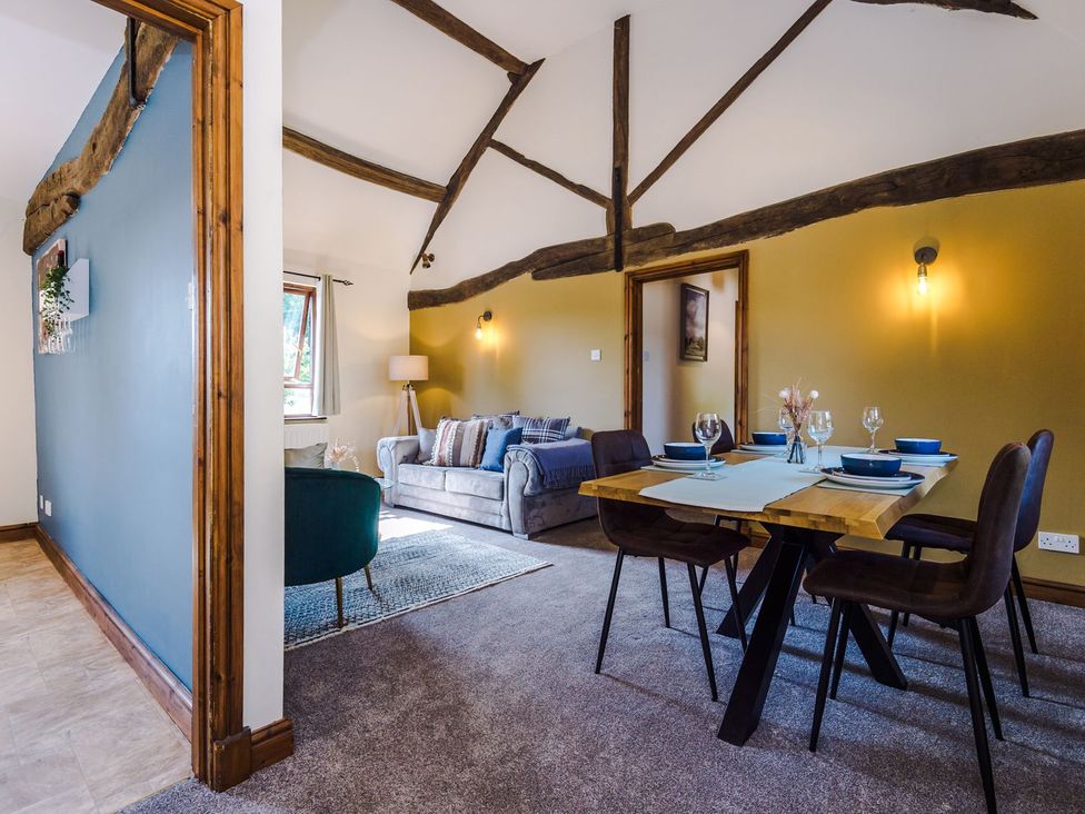 A living room with a sofa and dining area at Idris Barn