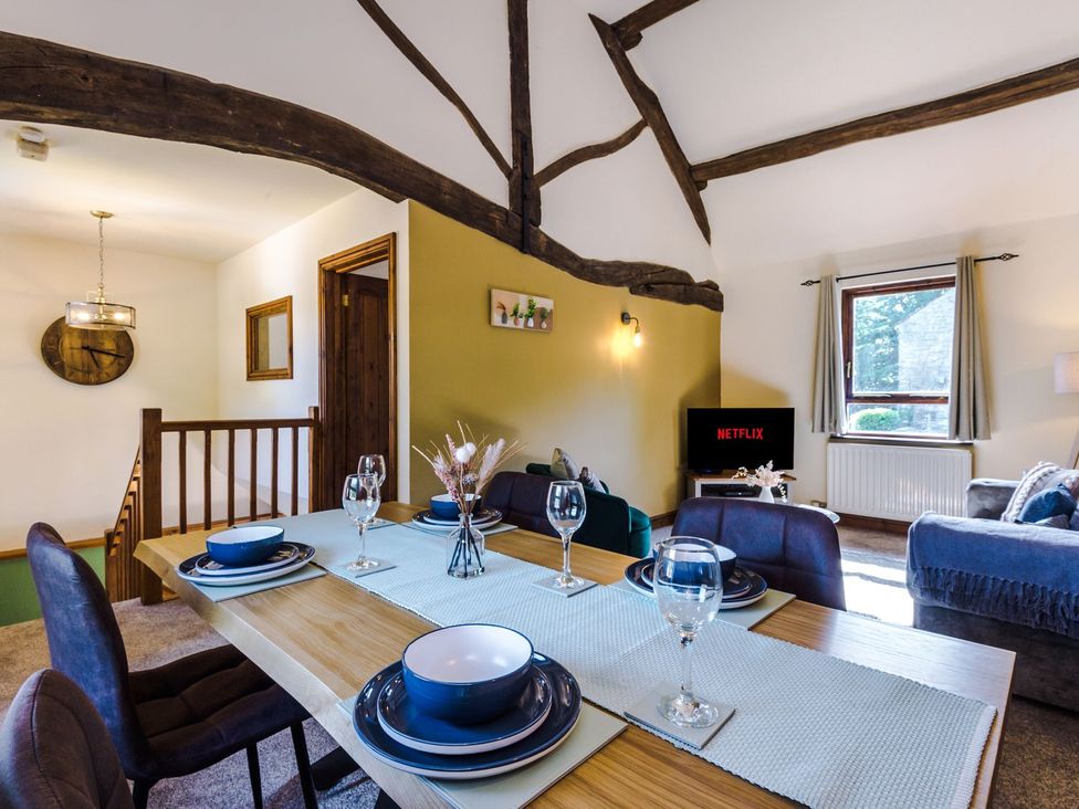 A dining area with a table set for meals and a television at Idris Barn