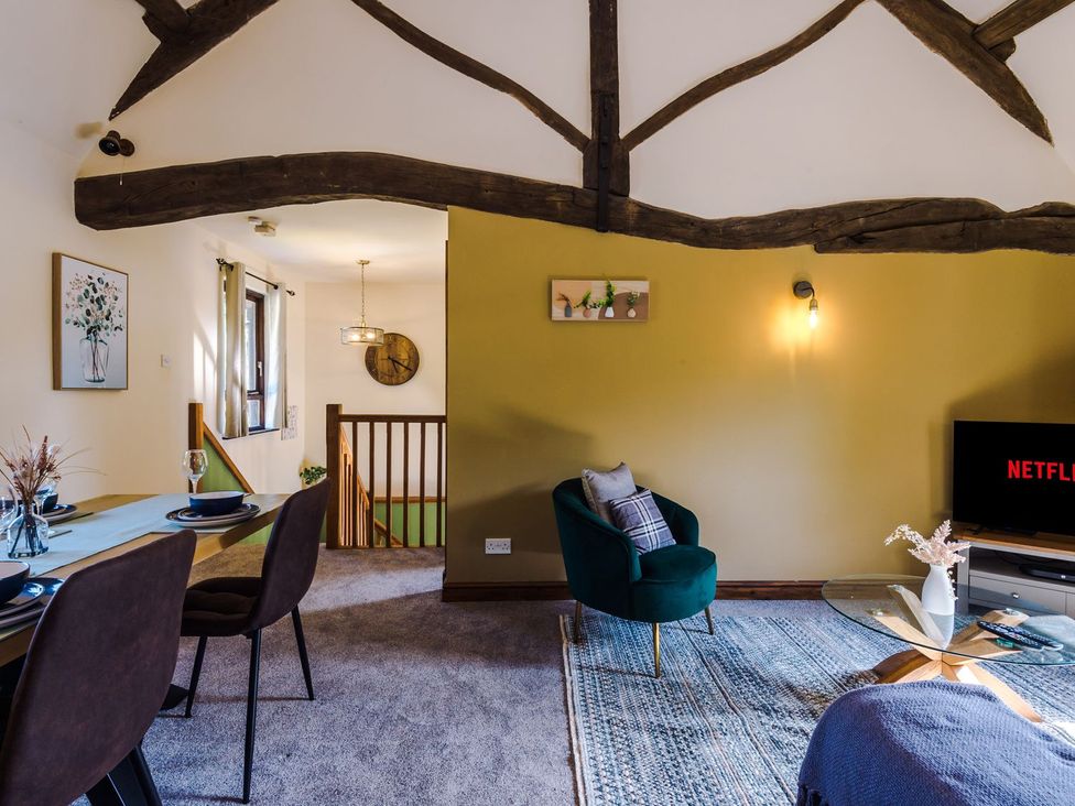A living room with a dining area and TV at Idris Barn