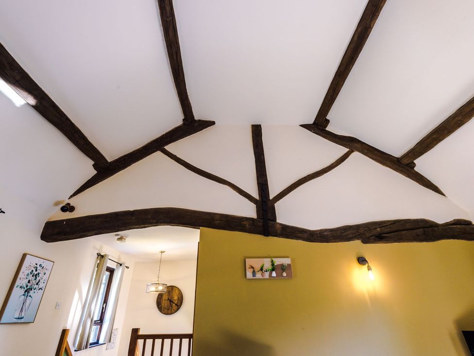 A living room with wooden beams and framed artwork at Idris Barn
