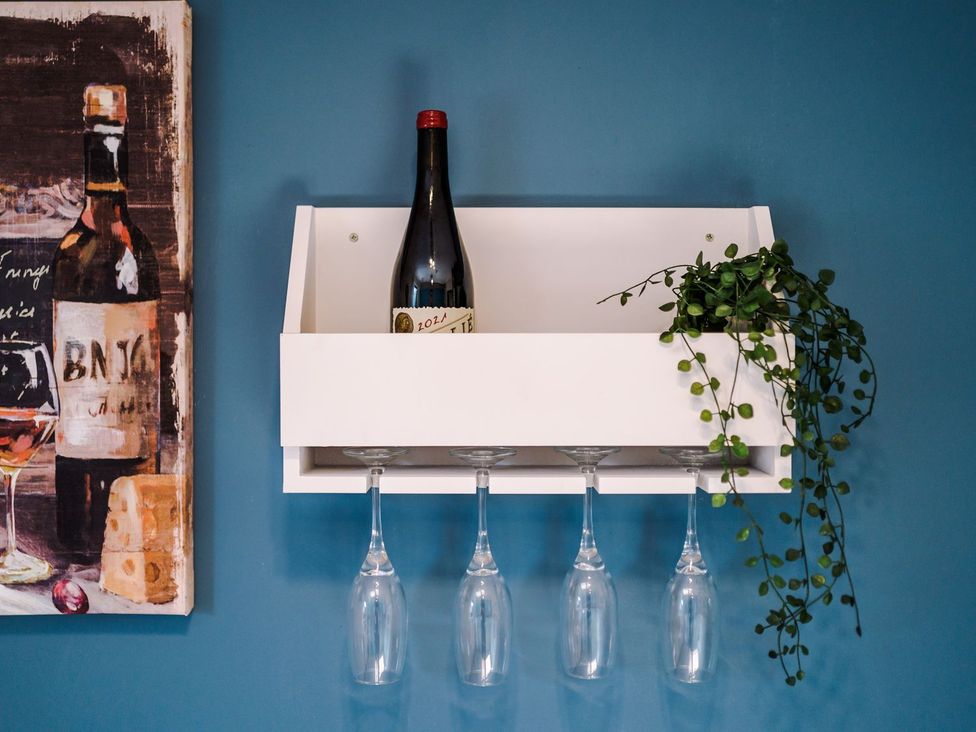 A shelf with a wine bottle and glasses on a blue wall at Idris Barn 