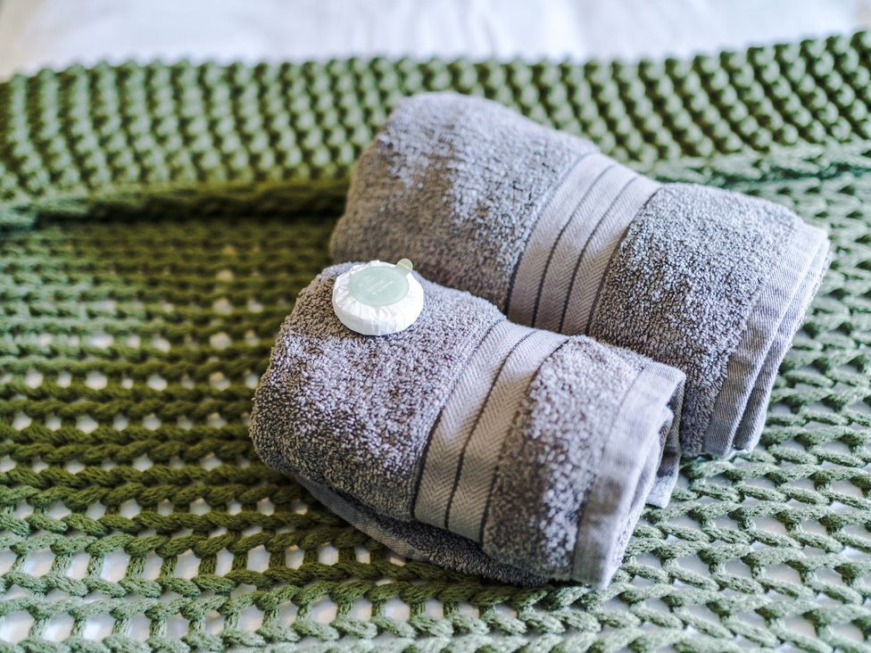 Towels and soap on a green woven bedspread at Idris Barn
