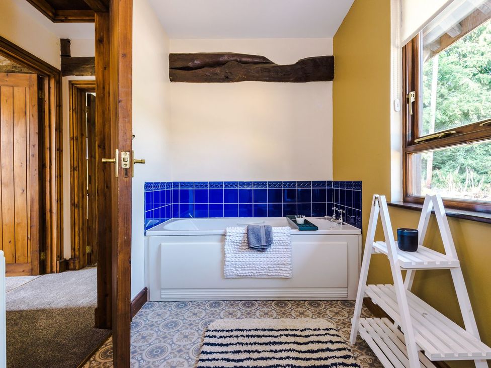A bathroom with a bathtub and shelving at Idris Barn