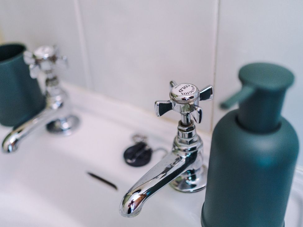 A sink with metal faucets and a soap dispenser at Idris Barn