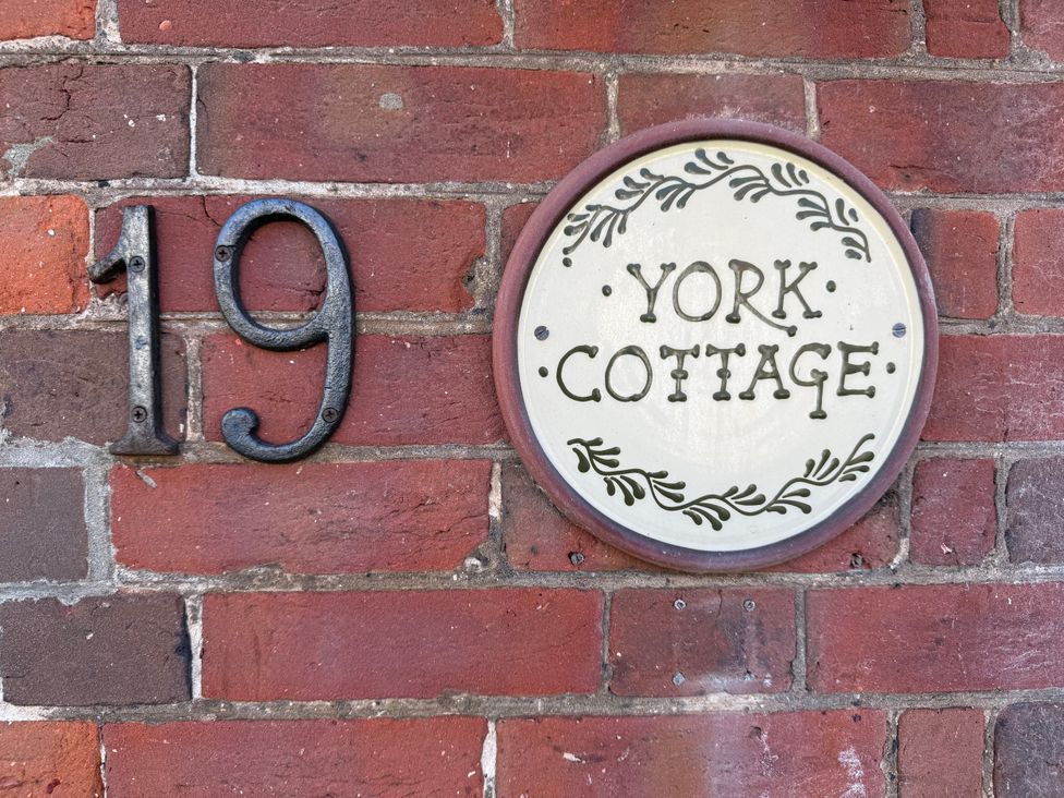 A house number and sign on a brick wall at York Cottage in Southwold
