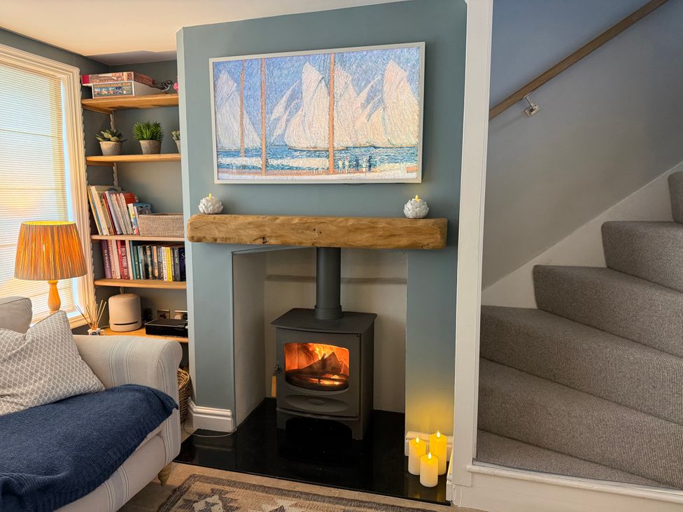 A living room with a fireplace and shelves filled with books at York Cottage in Southwold