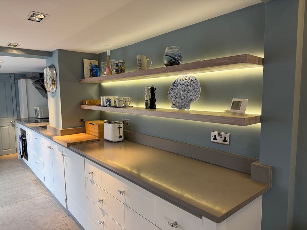 A kitchen counter with shelves and appliances at York Cottage Southwold