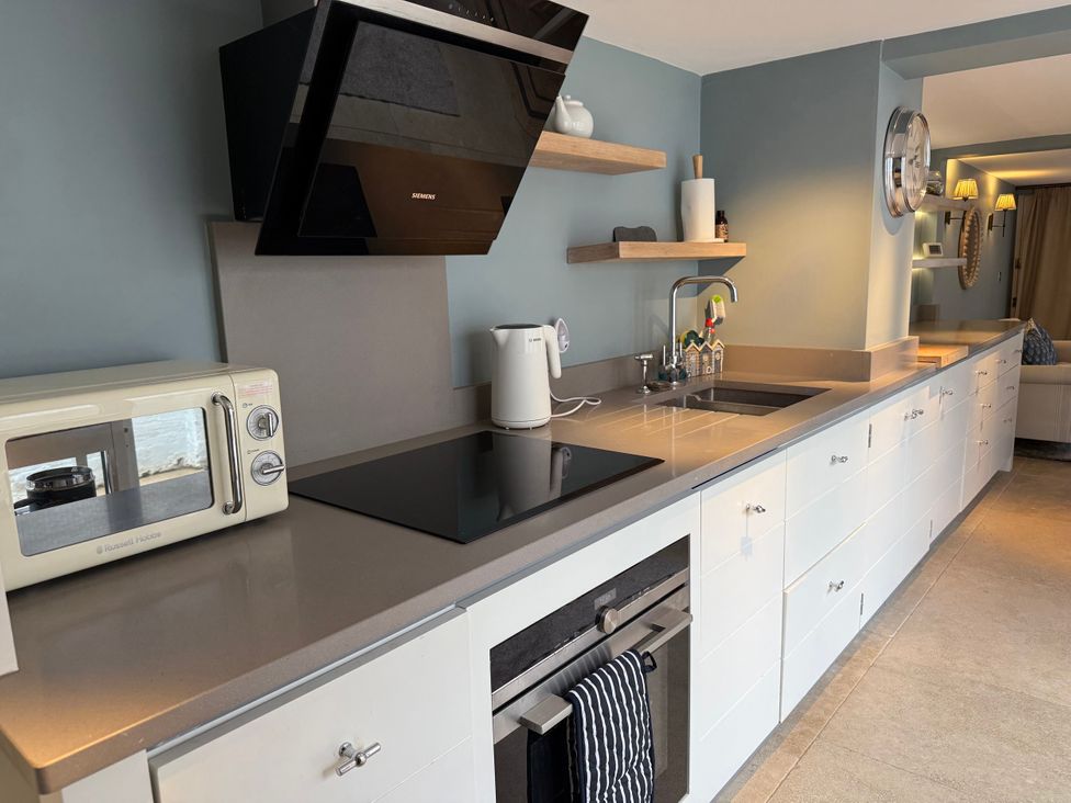 A kitchen with microwave, kettle, stove, and sink at York Cottage Southwold
