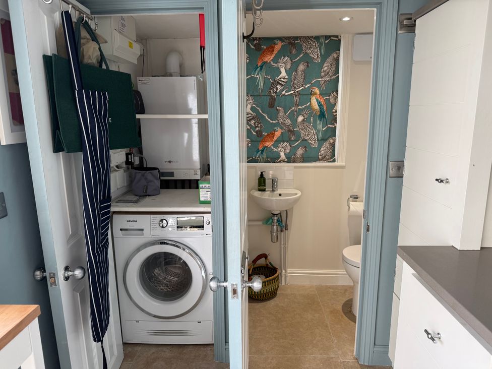 A utility room with a washing machine and sink at York Cottage in Southwold