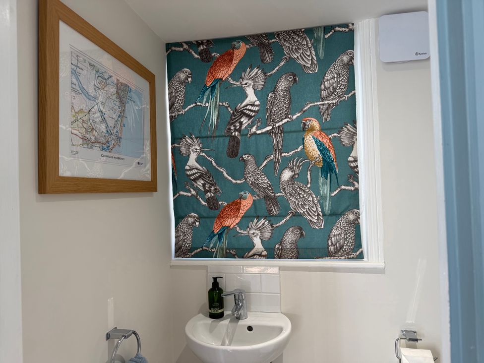 A bathroom with a map and bird patterned curtain at York Cottage Southwold