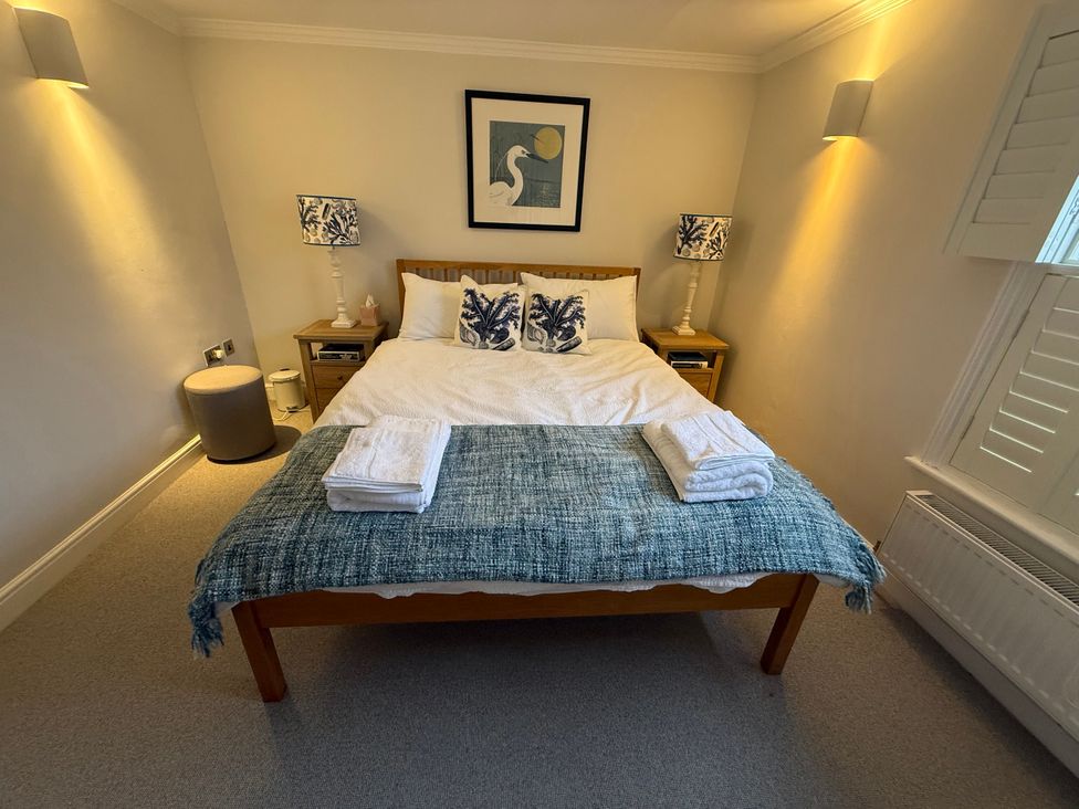 A bedroom with a bed, lamps, and towels at York Cottage in Southwold