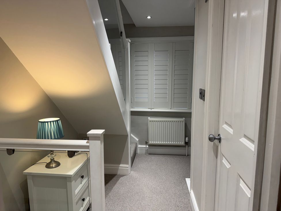A landing area with a lamp and radiator at York Cottage in Southwold