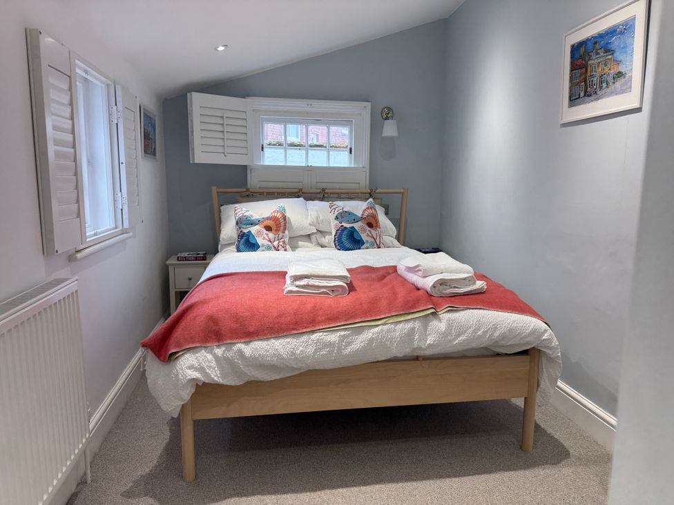 A bedroom with a bed and nightstand at York Cottage in Southwold