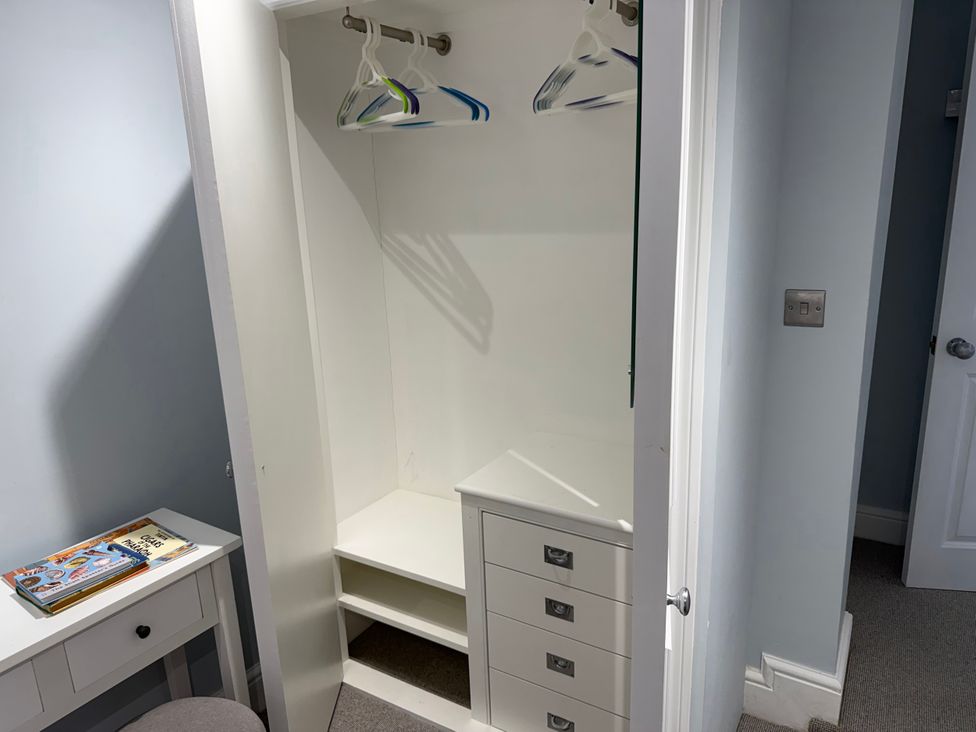 A wardrobe with hangers and drawers at York Cottage Southwold