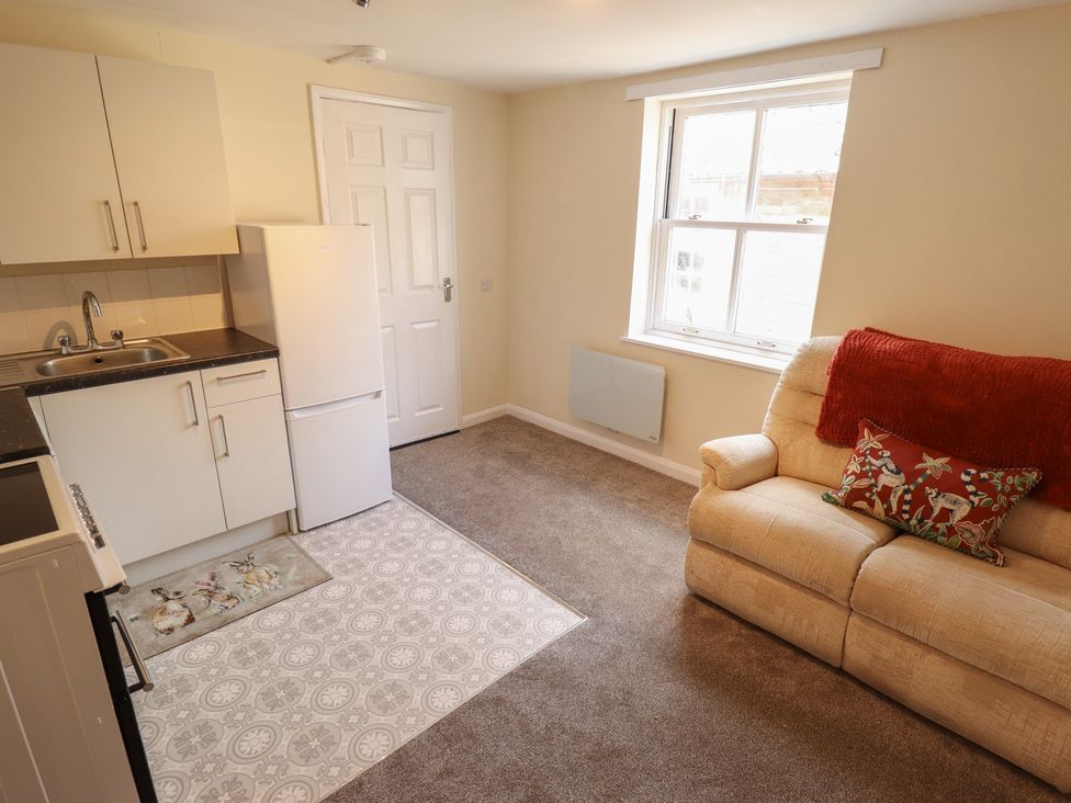 A living room with a kitchen area and a sofa at 29B High Street in Spilsby
