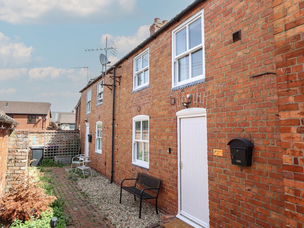 A courtyard with brick walls and a bench at Goldfinch in Spilsby