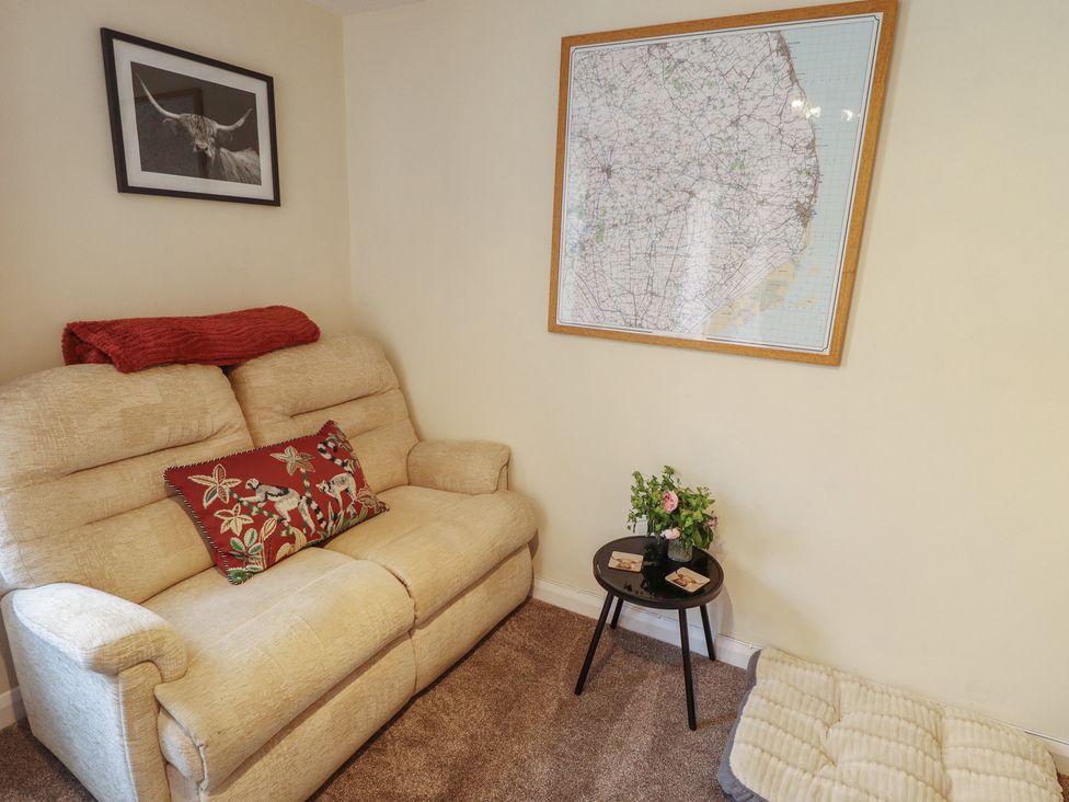 A living room with a sofa, map on the wall, and a table with flowers at Goldfinch, Spilsby