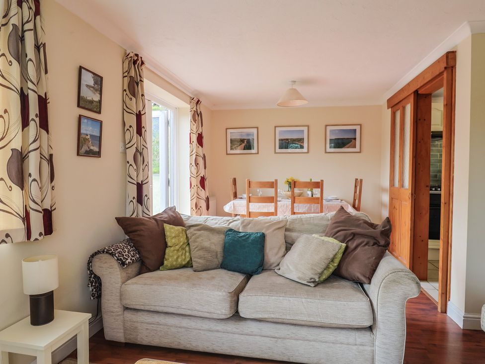 A living room with a sofa and dining table at Regenna in Seaton