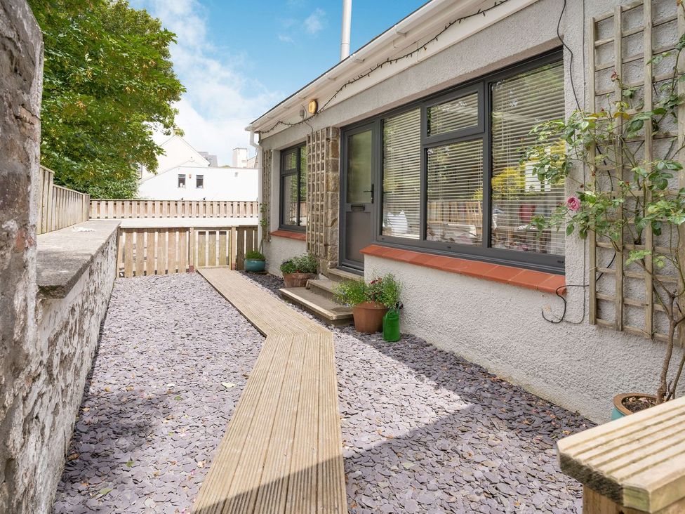 A garden with decking, pathway, and flower pots at Brewery Cottage in 