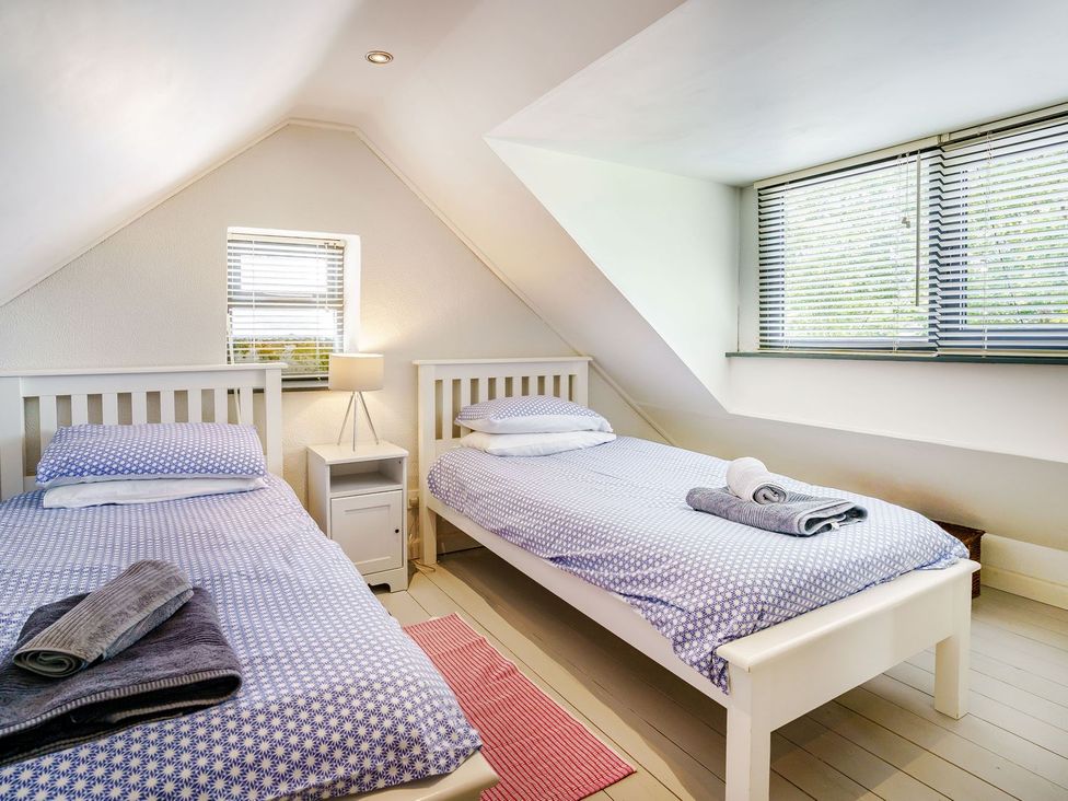 A bedroom with two beds and a nightstand at Brewery Cottage