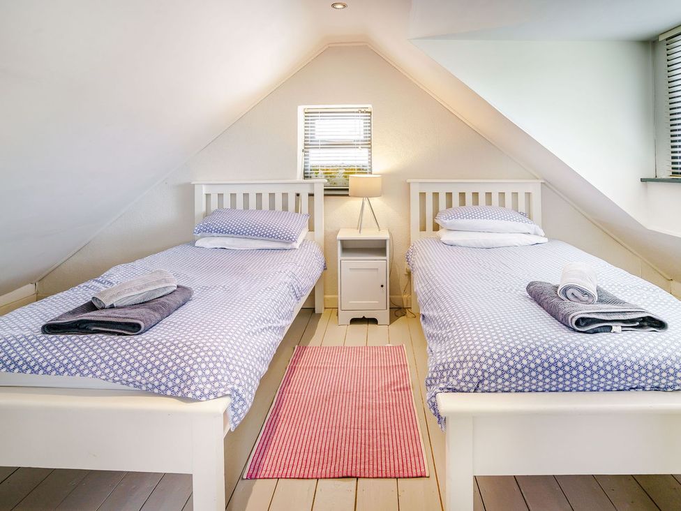 A bedroom with two single beds and a nightstand at Brewery Cottage