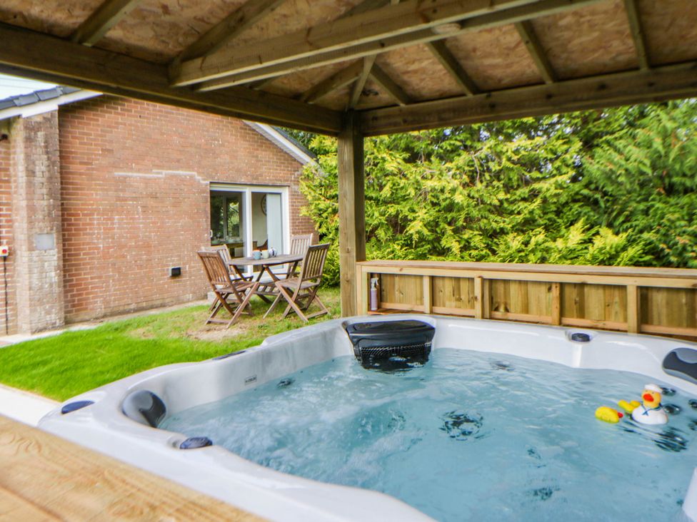 A garden with a hot tub and table with chairs at The Croft in Llandrindod Wells
