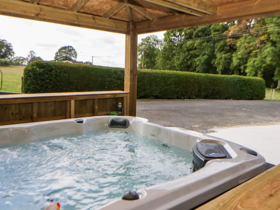 A hot tub under a wooden shelter at The Croft in Llandrindod Wells