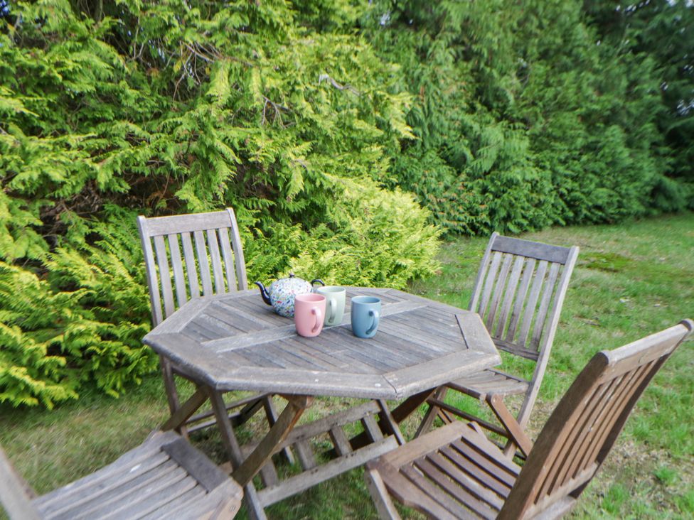 A garden with a wooden table and chairs with mugs and a teapot at The Croft in Llandrindod Wells