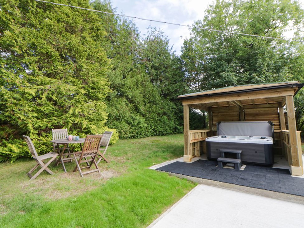 A garden with a table and chairs next to a hot tub at The Croft in Llandrindod Wells