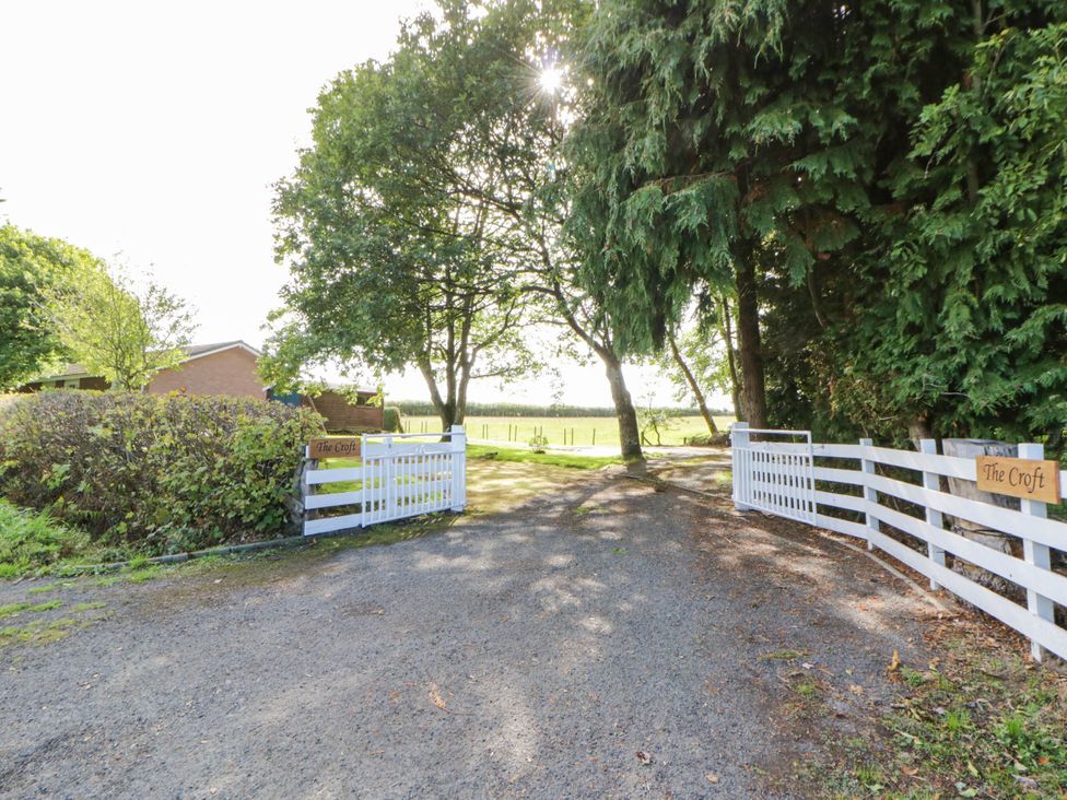 An entrance view of The Croft with a gravel path and trees in Llandrindod Wells