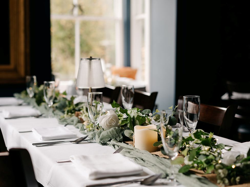 A dining table set with glasses and greenery at Picton House near St Clears