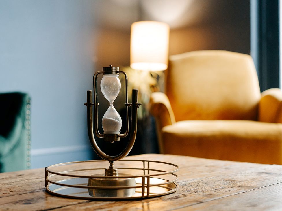 A living room with an hourglass and lamp on a coffee table at Picton House near St Clears