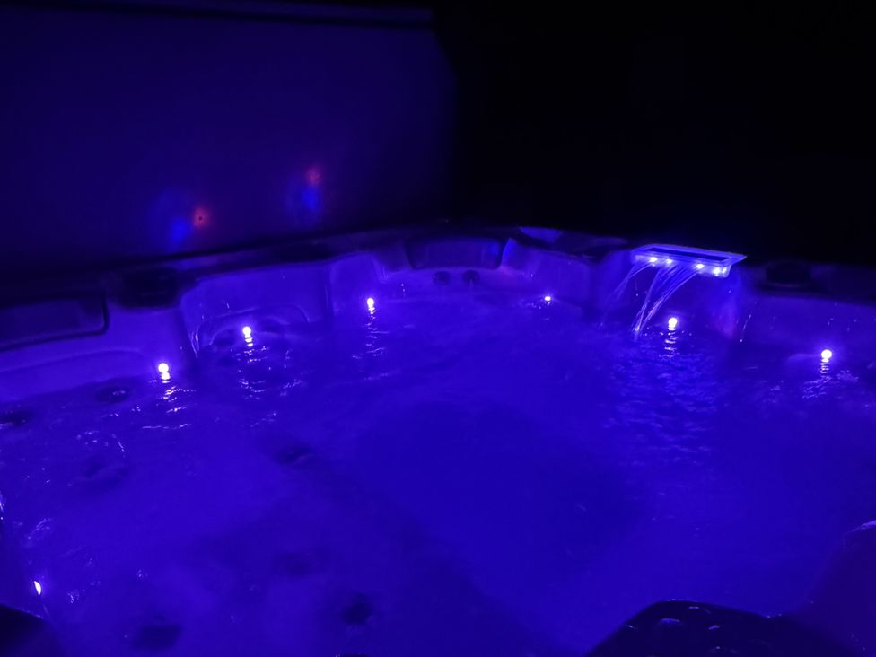 A hot tub with illuminated water in an outdoor area at Picton House near St Clears