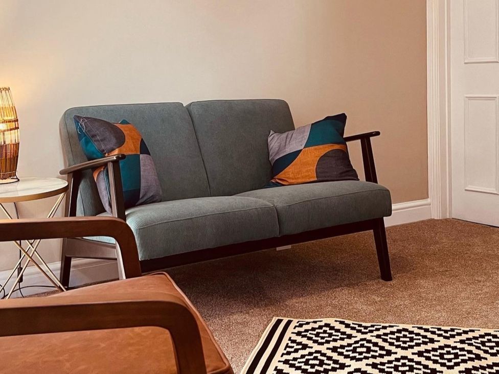 A living room with a sofa and a side table at Coach House near St Clears