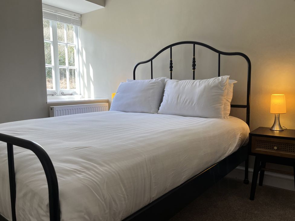 A bedroom with a bed and nightstand at Coach House near St Clears