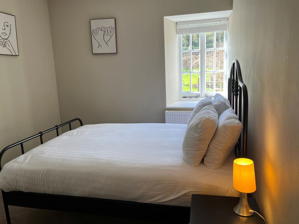A bedroom with a bed, lamp, and window at Coach House near St Clears