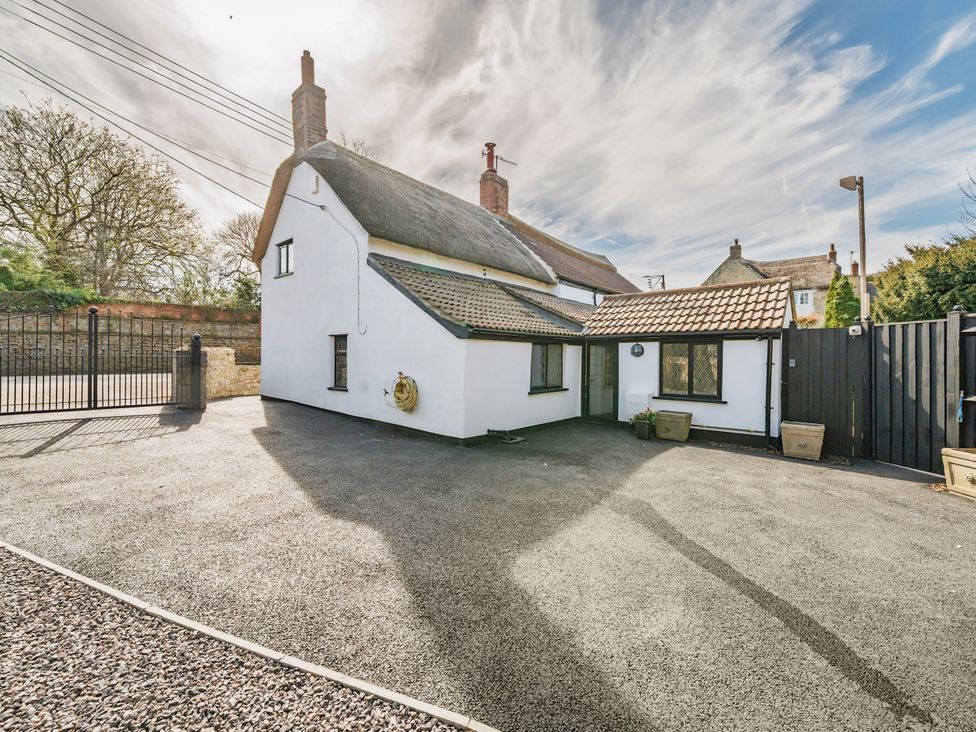 An outdoor view of a house with a garden and gate at Bridge Cottage in Chideock