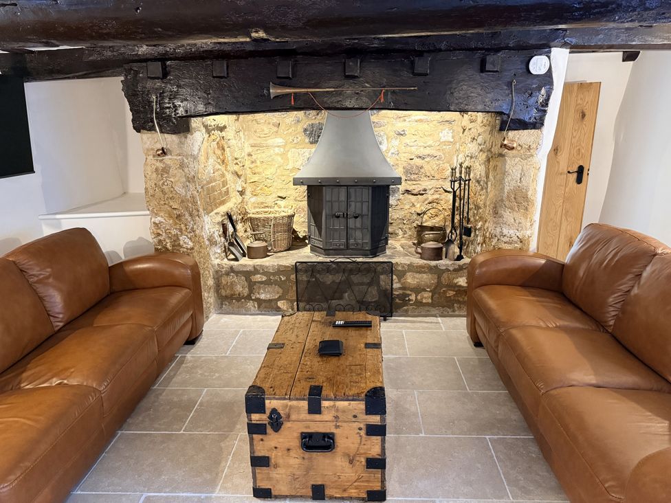 A living room with a fireplace and leather sofas at Bridge Cottage in Chideock
