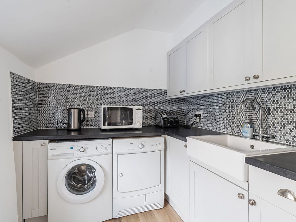 A kitchen with appliances including a washing machine and microwave at Bridge Cottage in Chideock