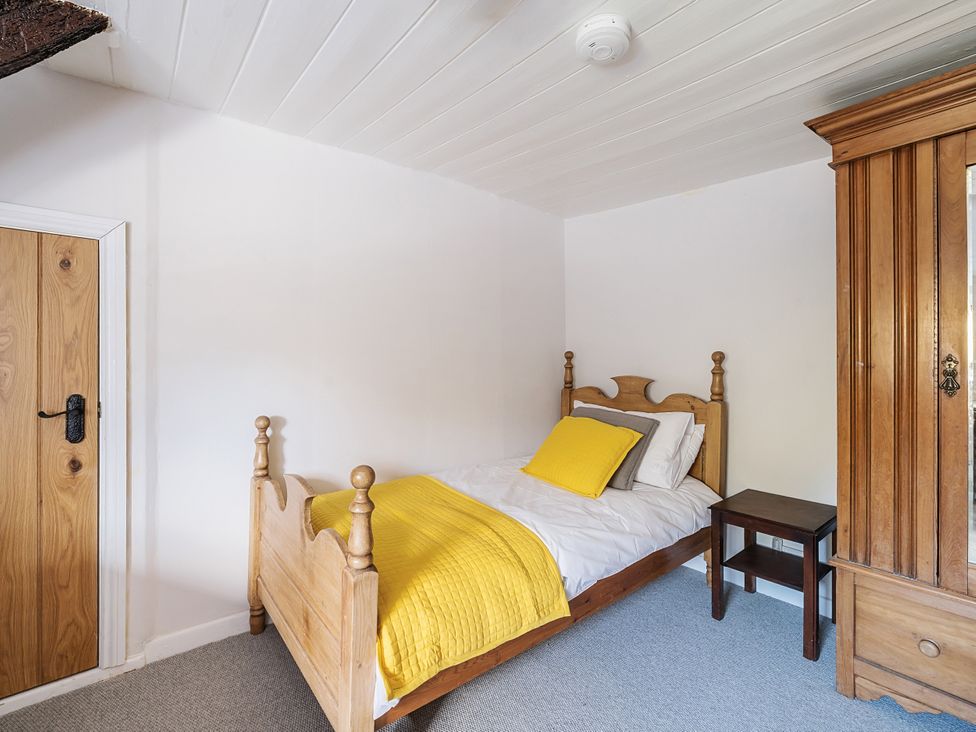 A bedroom with a bed and wardrobe at Bridge Cottage in Chideock